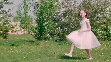 无忧无虑的女孩少年白色衣服运行开花草地水果花园阳光明媚的一天运行女孩跳夏天草坪上盛开的树果园